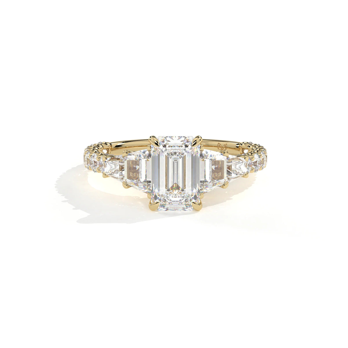 A yellow gold diamond ring featuring a large emerald-cut center stone flanked by smaller round and baguette-cut diamonds, set on a clean white background with a soft shadow.