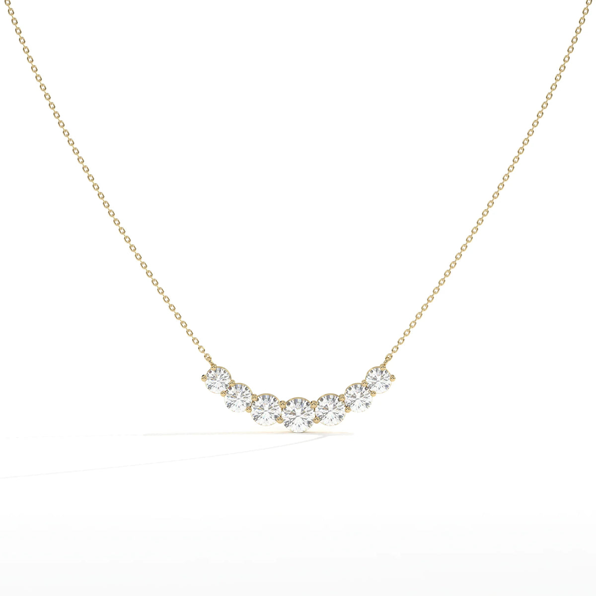 A delicate gold chain necklace featuring a curved row of five clear round-cut gemstones in a gold setting, displayed against a clean white background.