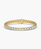 A yellow gold tennis bracelet featuring a continuous row of round-cut clear gemstones in a prong setting, with a matching gold clasp, shown on a white background.