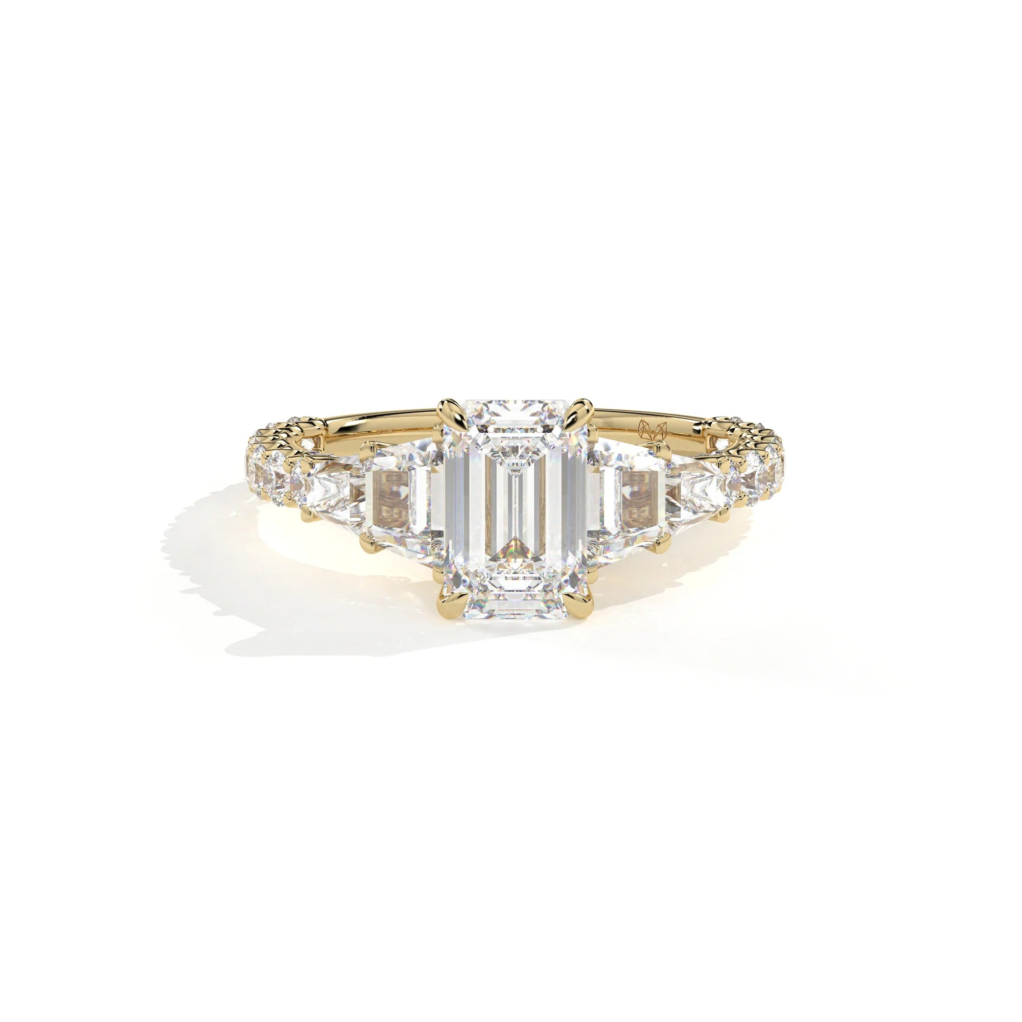 A yellow gold diamond ring featuring a large emerald-cut center stone flanked by smaller round and baguette-cut diamonds, set on a clean white background with a soft shadow.
