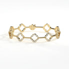 A gold bracelet featuring five interlocking quatrefoil links, adorned with small clear pavé diamonds, photographed on a clean white background.
