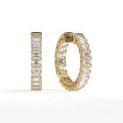 A pair of gold hoop earrings set with large rectangular clear gemstones, shown on a clean white background. One earring is displayed upright and the other is angled to show the side and back details.