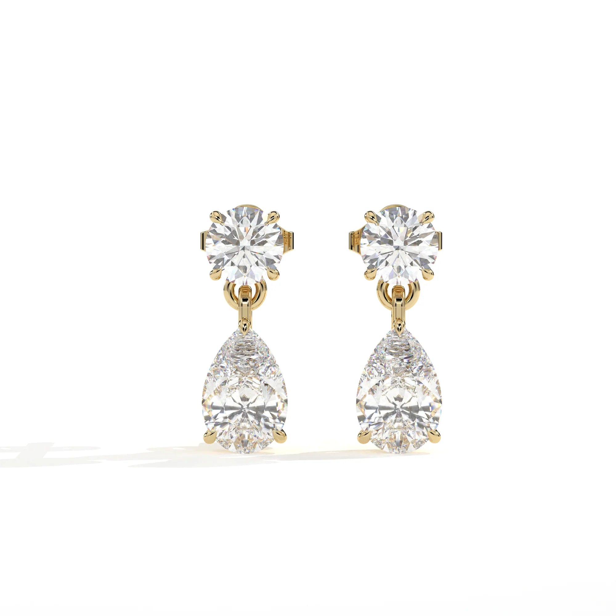A pair of gold drop earrings featuring a round brilliant-cut diamond stud on the top and a larger pear-cut diamond drop below, set against a clean white background.