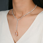 Necklace with a blush pink diamond pendant on a model wearing a white top.