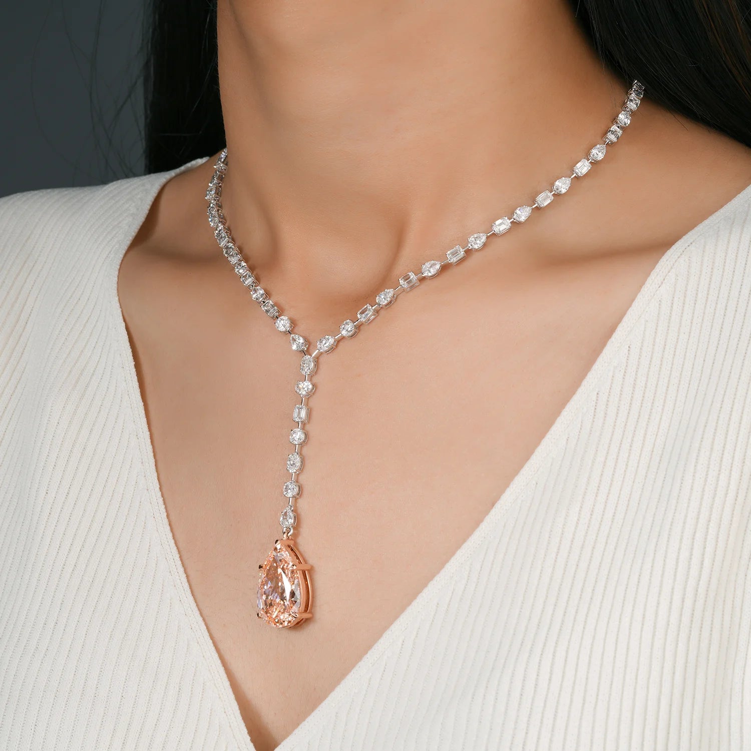 Necklace with a blush pink diamond pendant on a model wearing a white top.
