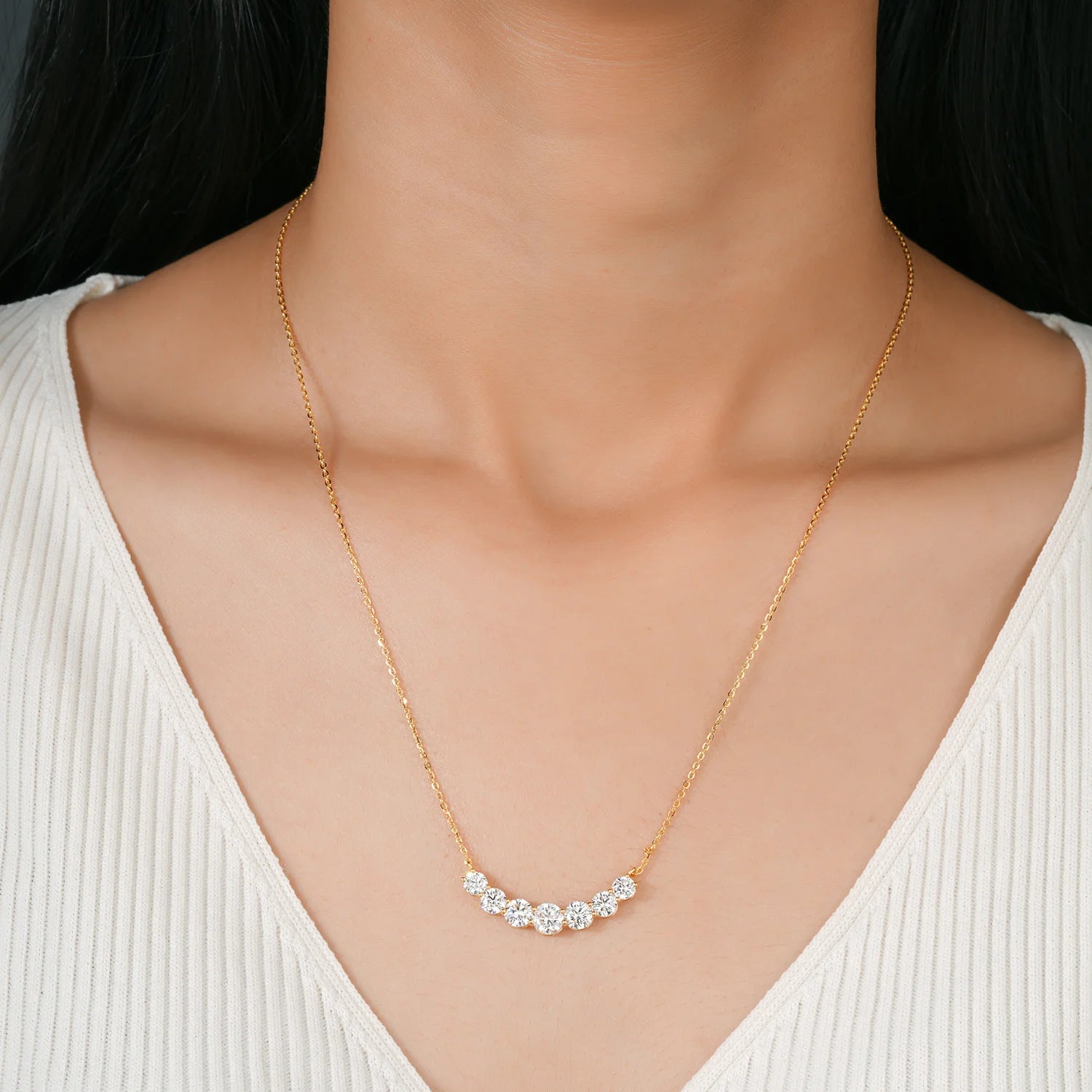 Gold necklace with small diamonds on a model wearing a white top