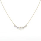 A delicate gold chain necklace featuring a curved row of five clear round-cut gemstones in a gold setting, displayed against a clean white background.