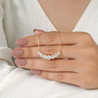 Gold necklace with diamonds held by a hand against a neutral background