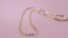 Gold chain necklace shines on a pink background.