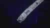 A sparkling diamond and sapphire tennis bracelet moves on a blue velvet background.