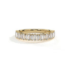 A yellow gold eternity ring featuring a row of baguette-cut clear diamonds, photographed on a clean white background with a soft shadow.
